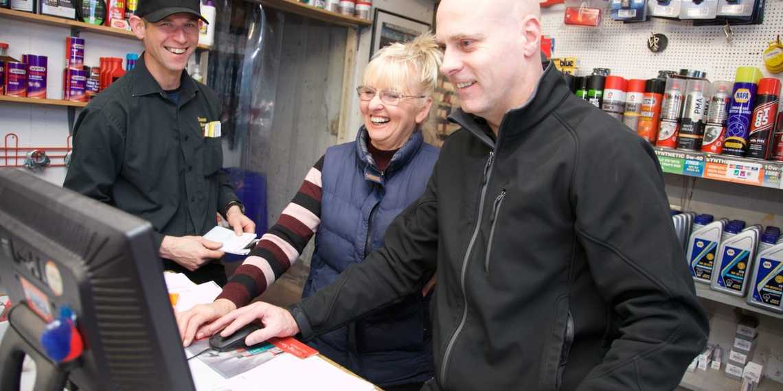 Members of the Eskside team looking at a computer screen behind the trade counter  